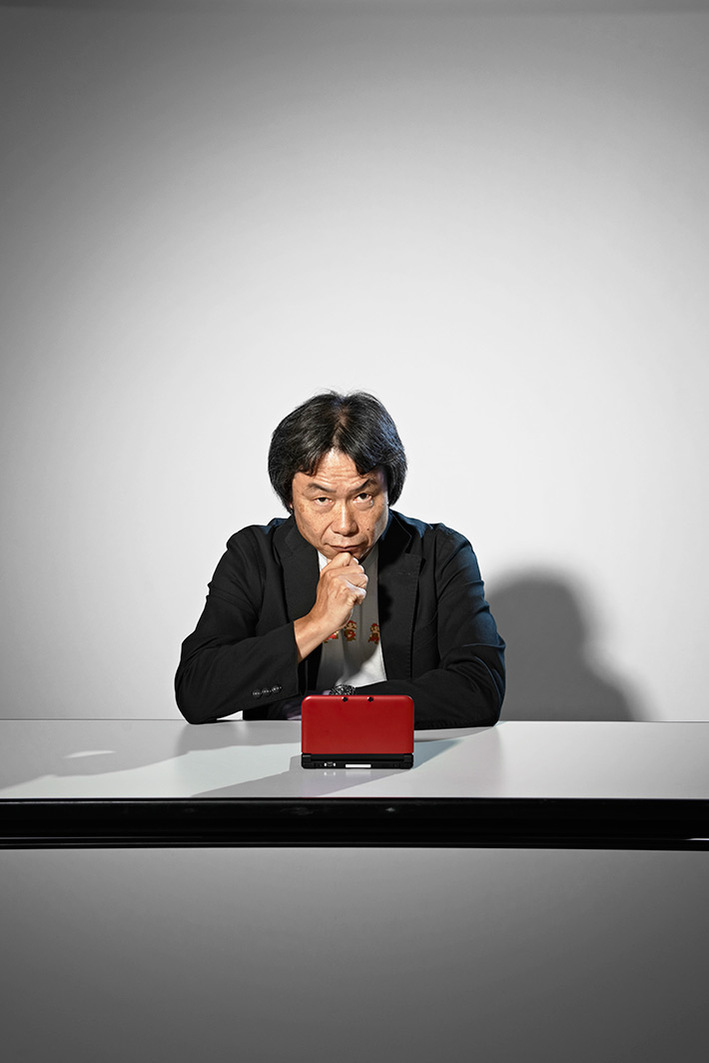 Miyamoto Shigeru sitting with a red Nintendo DS in front of him