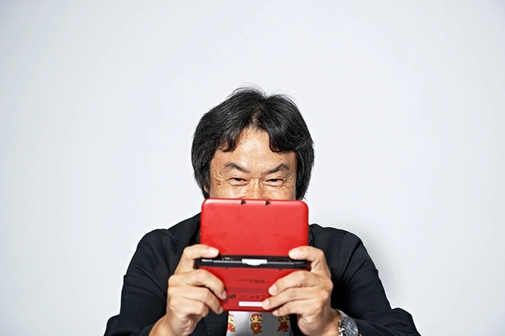 Portrait of Miyamoto Shigeru playing a nintendo DS
