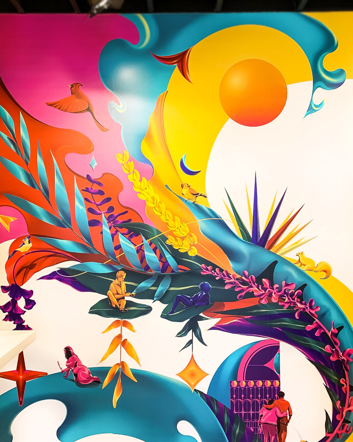 A vibrant and colourful mural depicts nature, people and plants.