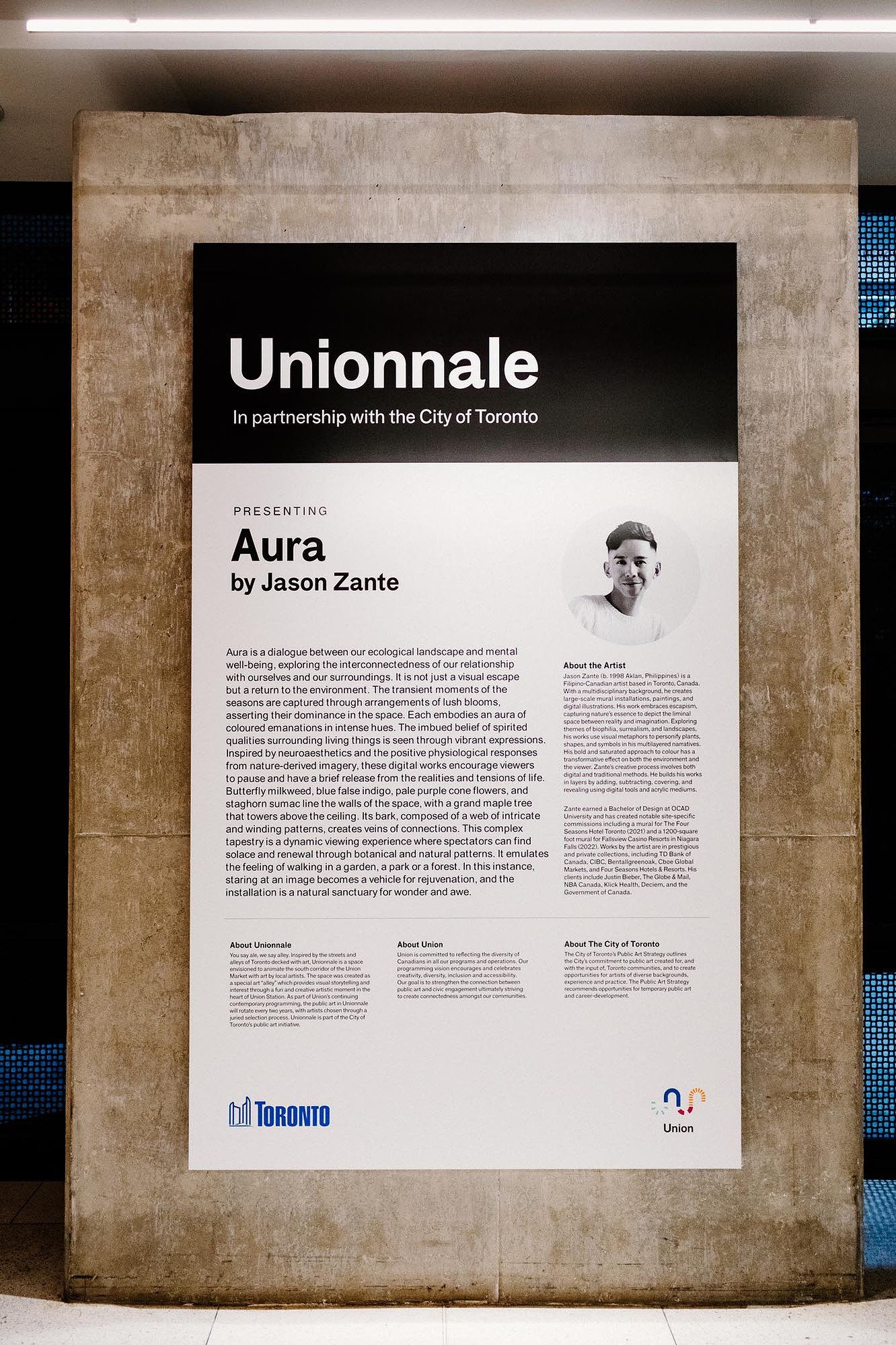 A didactic panel of an artwork exhibition is displayed on a wall.