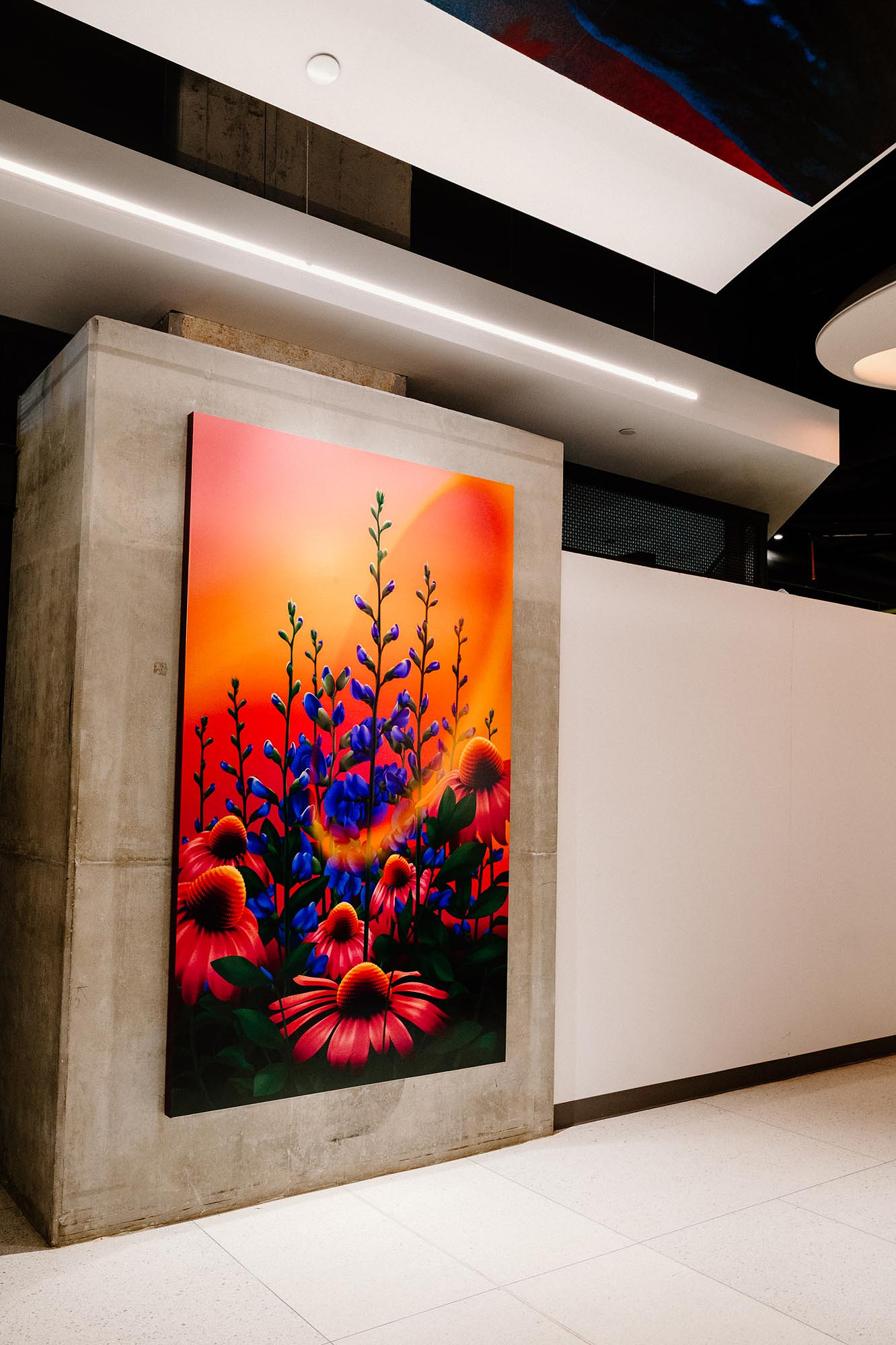 A vibrant artwork featuring shades of pink, purple, and red showcases flowers and plants on a wall.