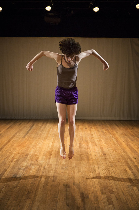 Quinn Hallenbeck dances Serenade in C at Velocity Dance Center in Seattle, she jumps high in the air and three shadows split on the empty stage.