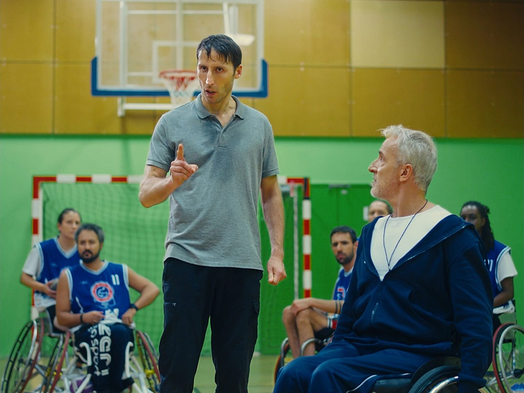 A man standing among players in wheelchair, Inadapté (2024), dir. Tristan Zerbib — cinematography Victor Zyński