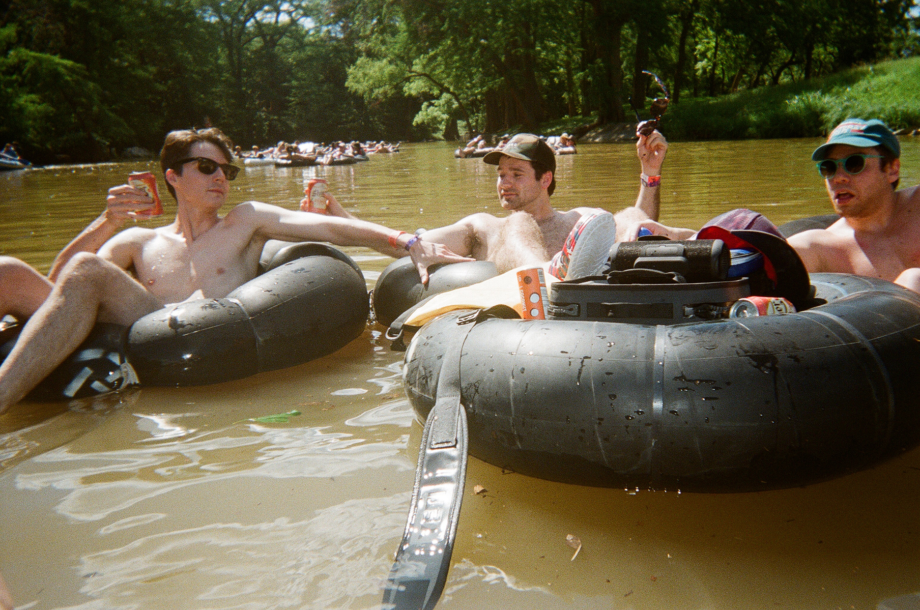 Three friends in inner tubes, floating the Comal River. 