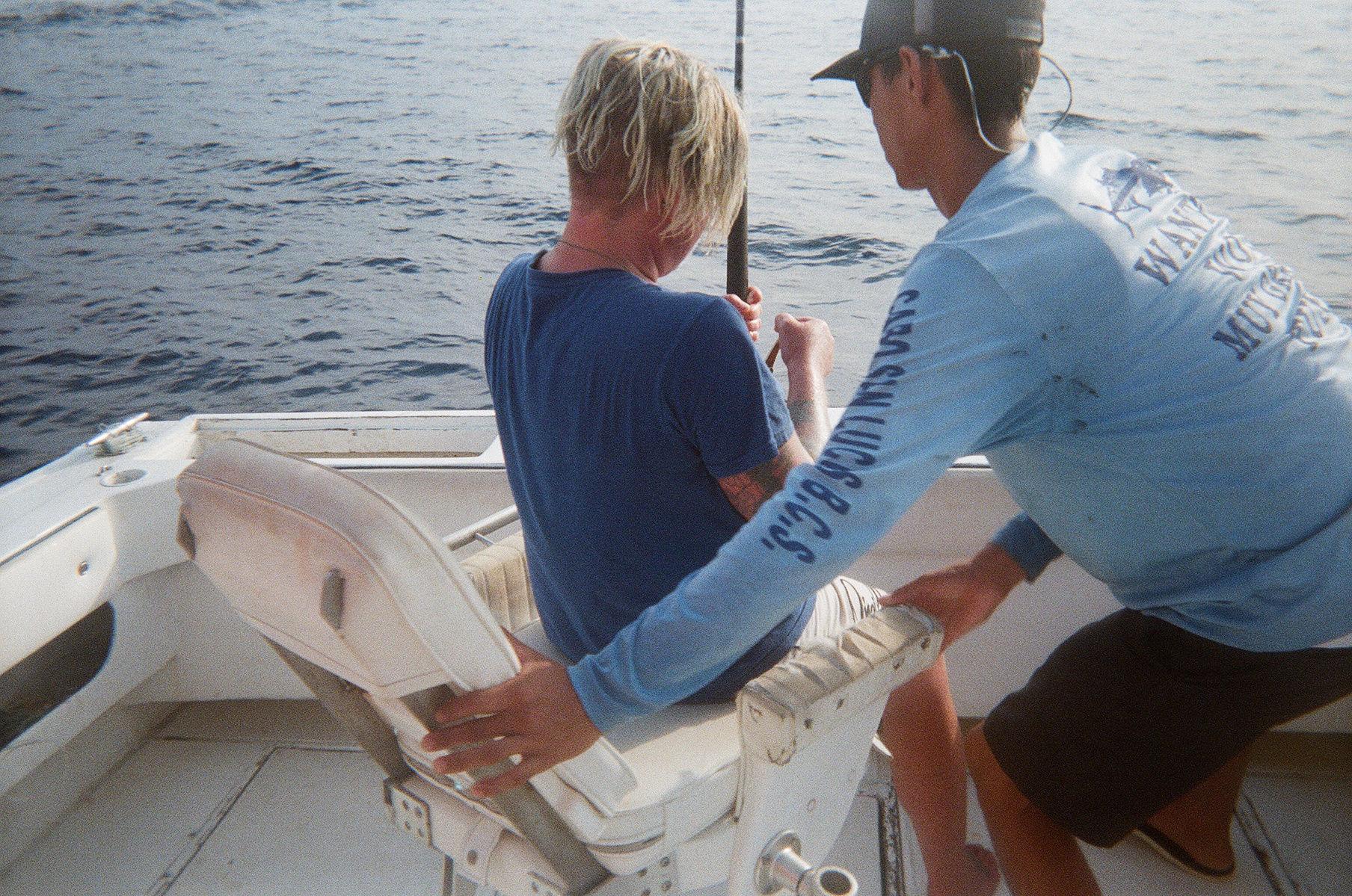 Tita and the mate reeling in a tuna fish from the boat.