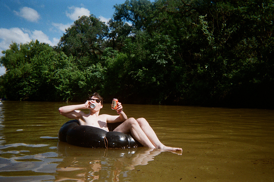 Diego double-fisting two peach Shiner beers on an innertube, mid-Comal River in New Braunfels, TX.