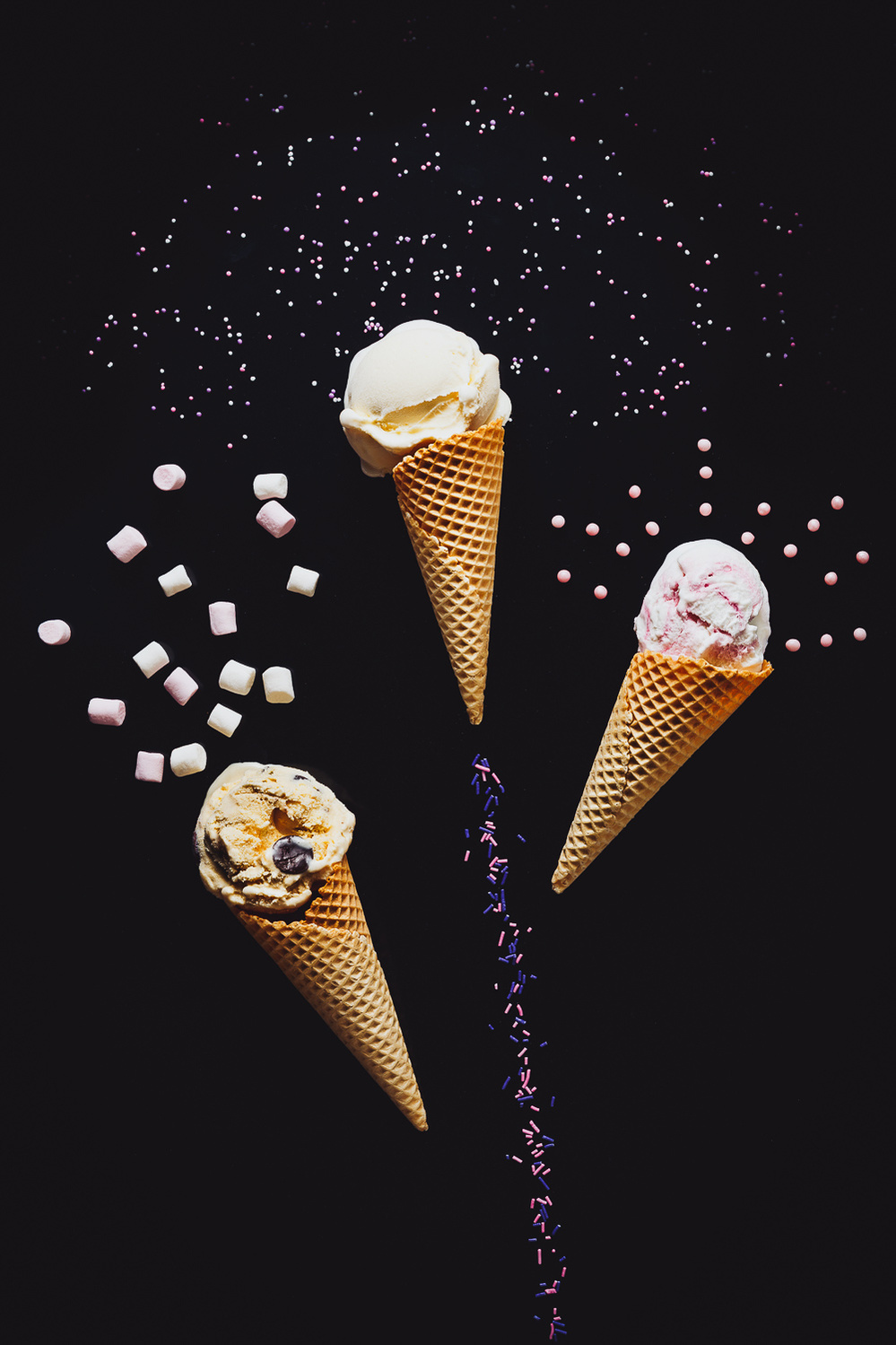 Three ice cream cones shooting into the air and exploding toppings like fireworks.