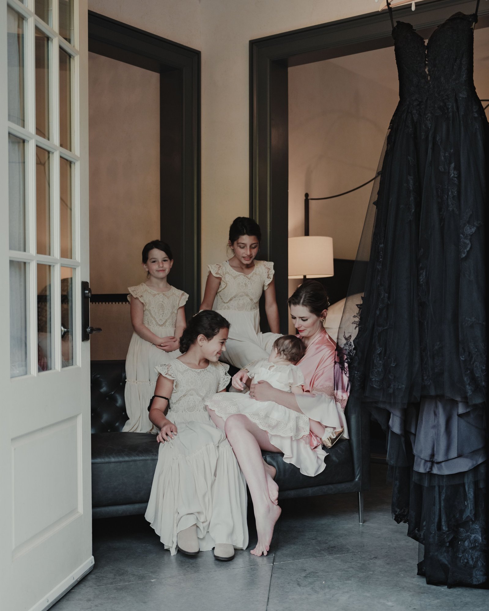 Daughters and flower girls surround a bride as she prepares to get into her black wedding dress before a wedding in Buena Vista, Colorado