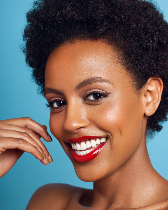 Image of a glowy brown skinned Black woman with a classic red lip