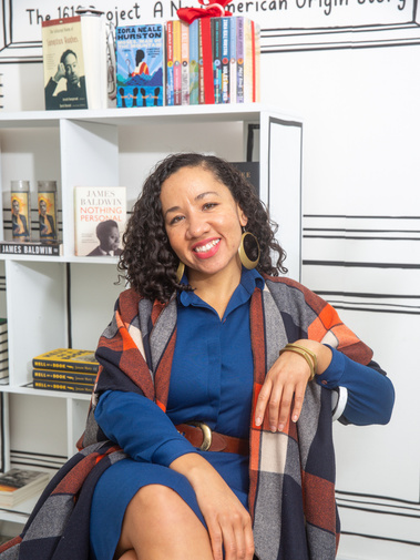 Author Camille Acker sitting in a chair and smiling.