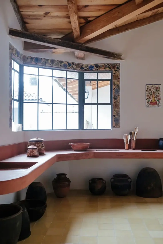 Earthenware pots in the home’s old kitchen are charred black from years of use over open flames. The painted tiles around the window were installed by Urzúa in the 1930s. Credit Ana Topoleanu