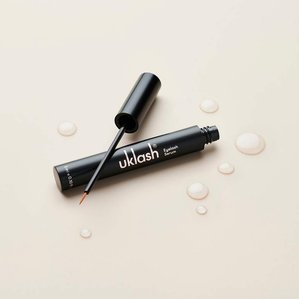 UKlash eyelash serum with eyelash brush and droplets of serum. Photographed and styled by cosmetic photographer Tom Hargreaves in his studio in Exeter, Devon
