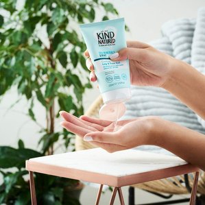 Model squeezing Kindnatured Sea minerals and mint leg and foot gel onto hand with plant and comfy chair in background. Photographed and styled by cosmetic photographer Tom Hargreaves in his studio in Exeter, Devon