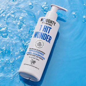 Noughty 1 hit wonder cleansing hair conditioner lying in water with bubbles around. Photographed and styled by cosmetic photographer Tom Hargreaves in his studio in Exeter, Devon