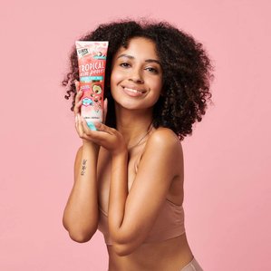 Smiling curly haired model with arm tattoo holding Dirty works tropical body wash.
Photographed and styled by cosmetic photographer Tom Hargreaves in his studio in Exeter, Devon