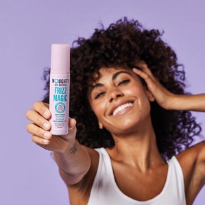 Model holding Noughty haircare Frizz magic anti frizz serum. Photographed and styled by cosmetic photographer Tom Hargreaves in his studio in Exeter, Devon