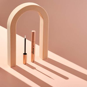 Uklash eyebrow serum in archway with sun style light from behind creating strong shadows. Photographed and styled by cosmetic photographer Tom Hargreaves in his studio in Exeter, Devon