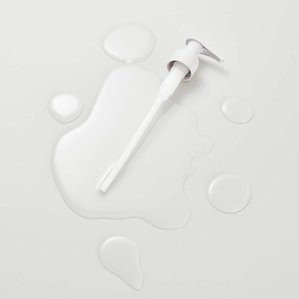 Noughty Haircare nozzle in puddle of product. Photographed and styled by cosmetic photographer Tom Hargreaves in his studio in Exeter, Devon