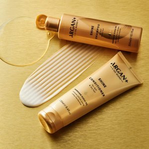 Argan+ shine shampoo &amp;amp;amp; conditioner with product swatches on a metallic gold background. Photographed and styled by cosmetic photographer Tom Hargreaves in his studio in Exeter, Devon