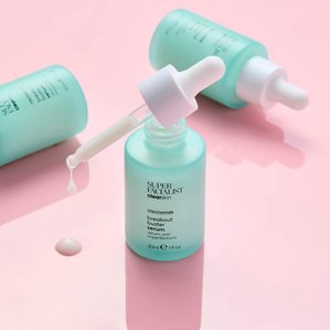 Superfacialist clear skin breakout buster serum with product dripping out of pipette on pink gloss acrylic. Photographed and styled by cosmetic photographer Tom Hargreaves in his studio in Exeter, Devon