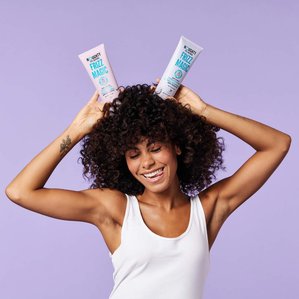 Model holding Noughty haircare Frizz magic shampoo &amp;amp; conditioner above head like rabbitt ears. Photographed and styled by cosmetic photographer Tom Hargreaves in his studio in Exeter, Devon