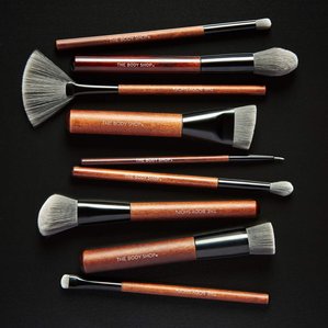 A selection of The Bodyshop makeup brushes lying on a black ground. Photographed and styled by cosmetic photographer Tom Hargreaves in his studio in Exeter, Devon
