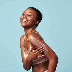 Smiling Model for Superfacialist applying body scrub to her arm. Photographed and styled by cosmetic photographer Tom Hargreaves in his studio in Exeter, Devon