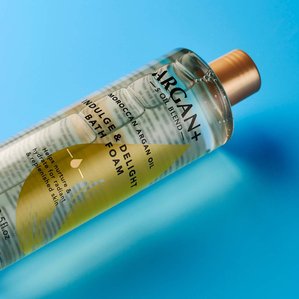Closeup of Argan+ Indulge &amp;amp; delight bath foam lying on blue backdrop. Photographed and styled by cosmetic photographer Tom Hargreaves in his studio in Exeter, Devon