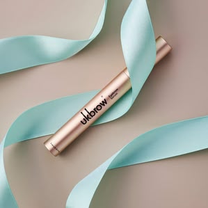 Uklash Eyebrow serum lying in festive ribbon. Photographed and styled by cosmetic photographer Tom Hargreaves in his studio in Exeter, Devon