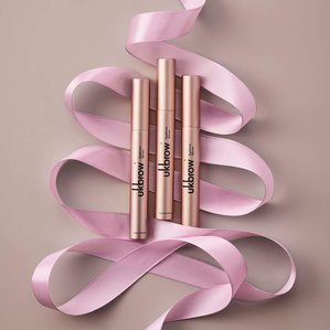 3 Uklash Eyebrow serums lying in pink ribbons shaped like a Christmas tree. Photographed and styled by cosmetic photographer Tom Hargreaves in his studio in Exeter, Devon
