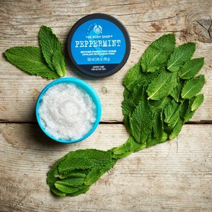 The Bodyshop peppermint foot scrub with a footprint of mint leaves. Photographed and styled by cosmetic photographer Tom Hargreaves in his studio in Exeter, Devon