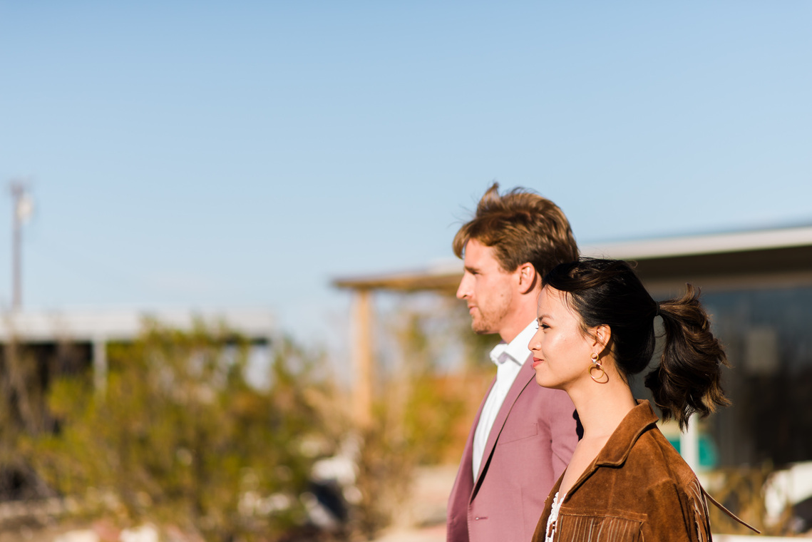 A bride and groom walk through the yard of a funky AirBnB in the California desert