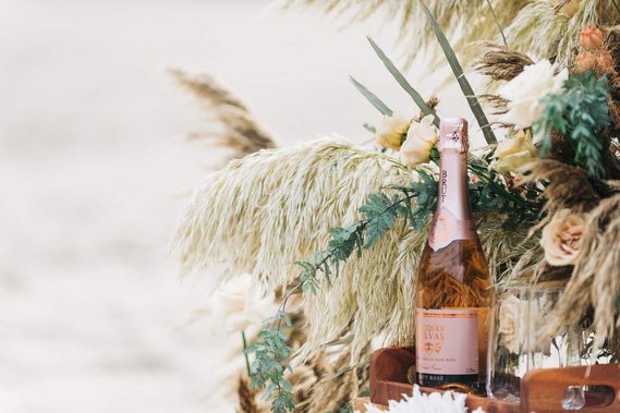 A close-up of the couple's styled picnic, which includes a bottle of champagne surrounded by luxurious florals