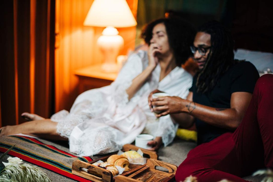 The bride and groom enjoy a breakfast in bed consisting of fresh pastries and coffee
