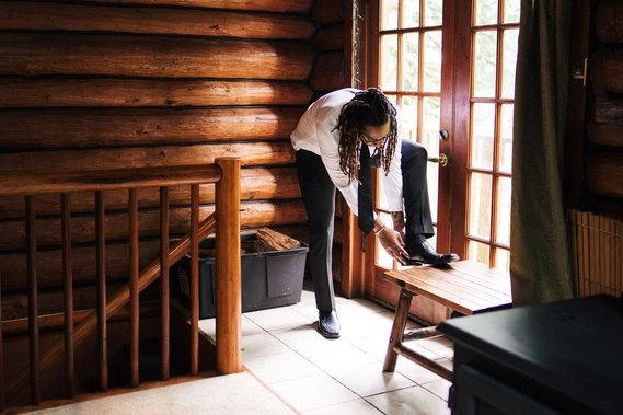 The groom adjusts his shoe as he gets dressed