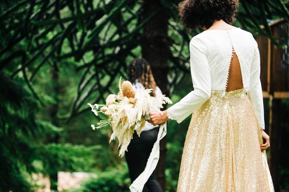 The bride approaches the groom for a first look outside their forest cabin