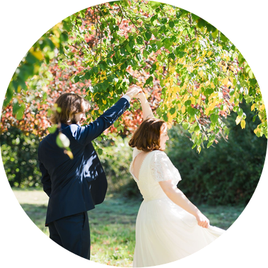 A groom twirls his bride under his arm as they dance  in a colorful orchard