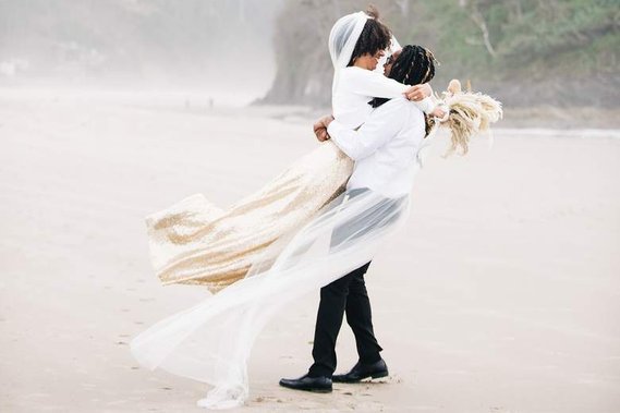 The groom lifts the bride and twirls her around on the beach