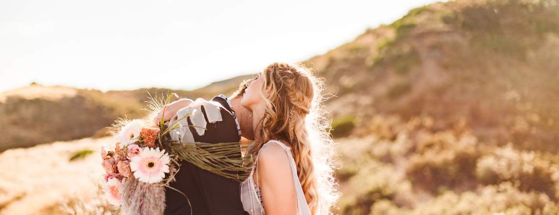 the groom rests his head against his bride's shoulder as she wraps her arm around him at their elopement