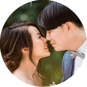 A bride and groom bring their faces close together and touch noses gently