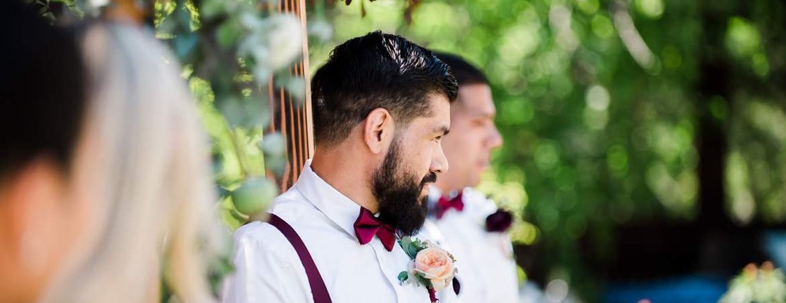 5 Reasons to Have an Intimate Wedding
(that have nothing to do with money): A groom stands by a floral wedding arch as he watches his bride arrive for their ceremony