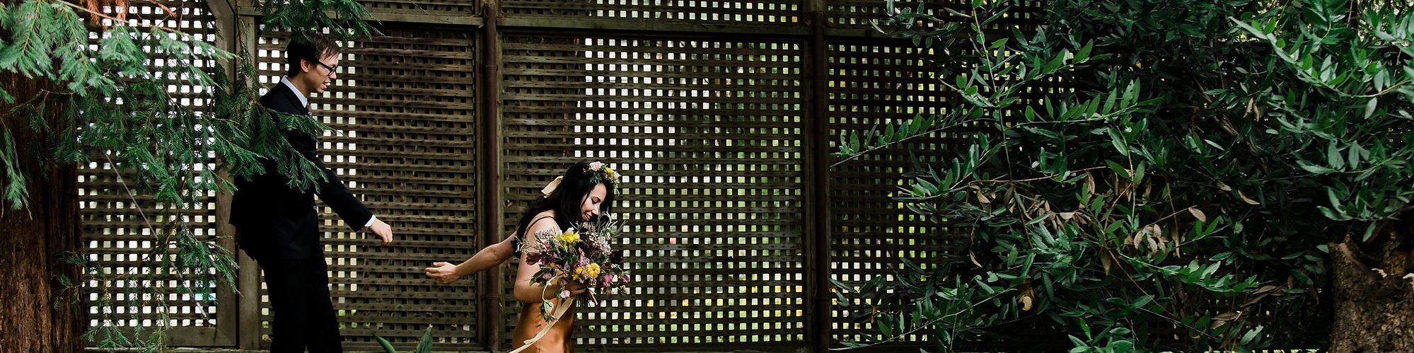 A bride and groom walk together through the couple's backyard after their home wedding ceremony