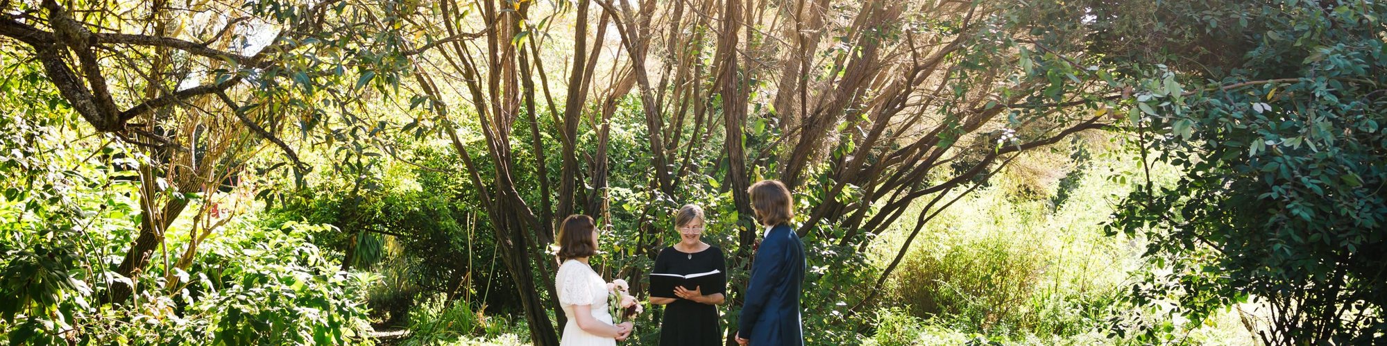 A bride and groom celebrate their elopement ceremony under a tea tree in a private garden