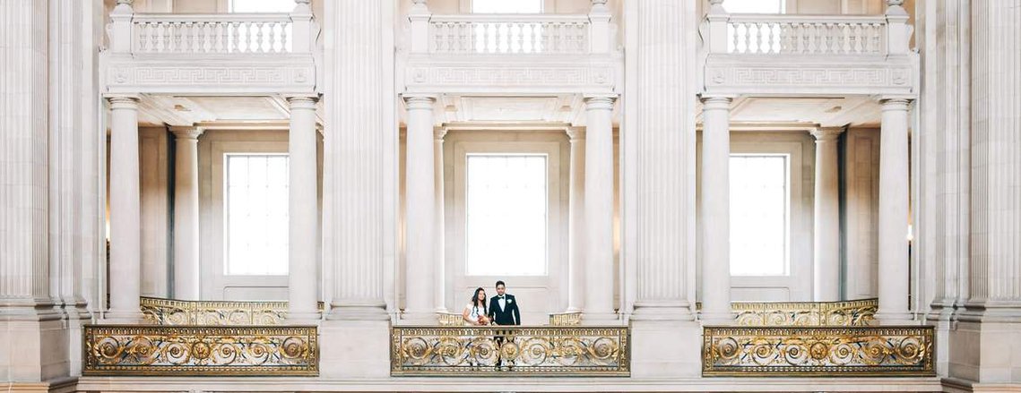 a young couple stands among the opulent columns of San Francisco City Hall, where they have just eloped