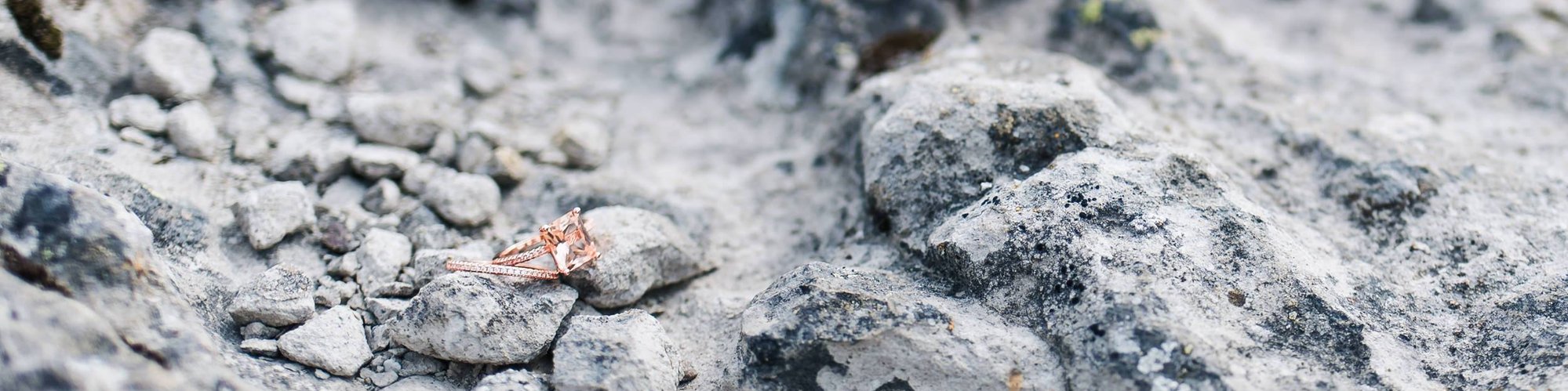 A pair of rose-gold rings glitters against textured white rocks in the Napa County mountains