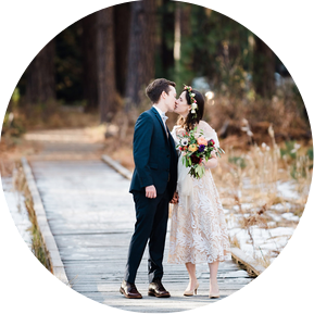 An eloping bride and groom pause for a kiss as they walk through a frosty meadow in Yosemite National Park