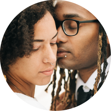 A bride and groom bring their faces together so that they are almost touching; they close their eyes and breathe