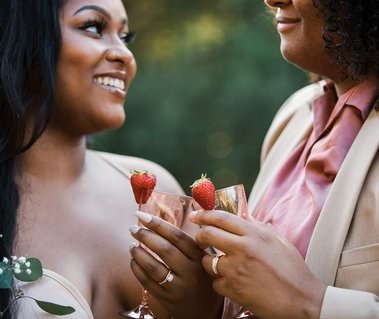 Two brides toast to each other with pink lemonade
