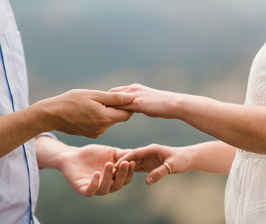 A bride and groom's hands touch as they prepare to exchange rings