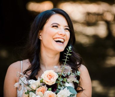A bride laughs over her bouquet